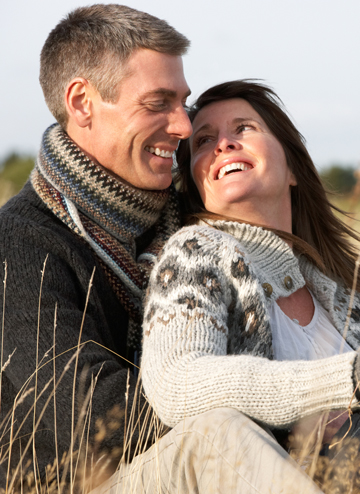 Man and woman seated outdoors. She is looking back over her shoulder.